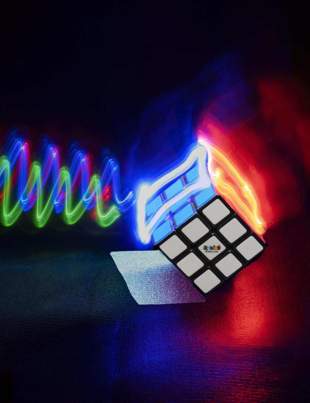 Rubik cube covered in red, blue, and green light.